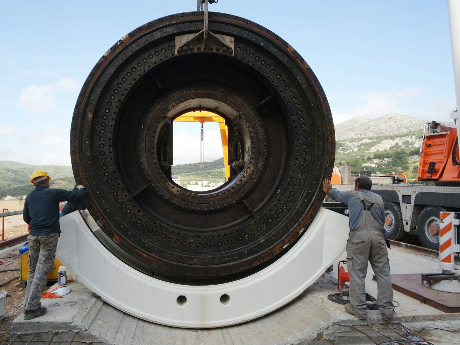 Crew standing beside a large coated pipe section in a fabrication yard