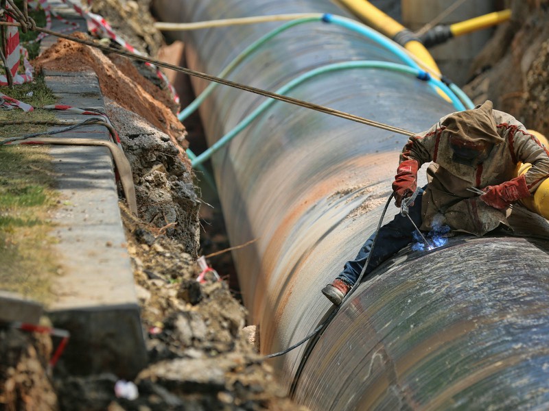Welder working on a large-diameter pipe in a construction trench