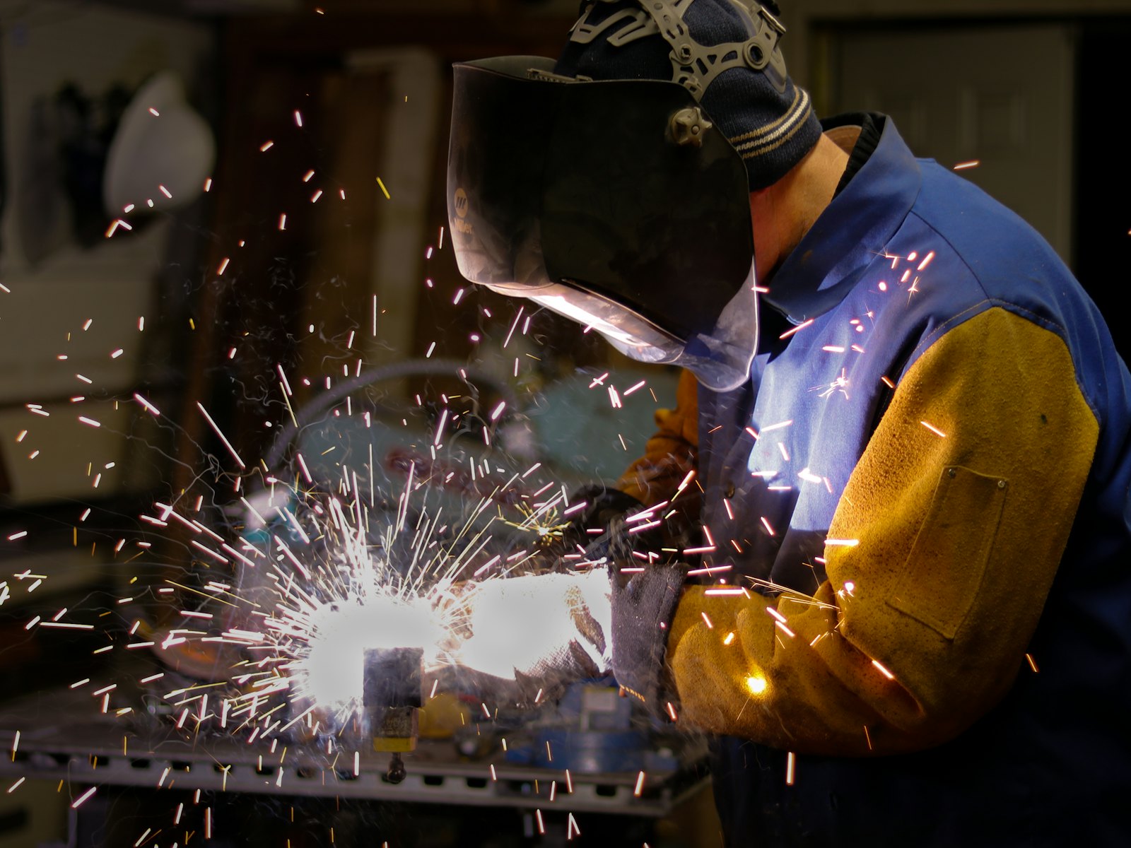 Welder in protective gear with sparks flying in a fabrication shop